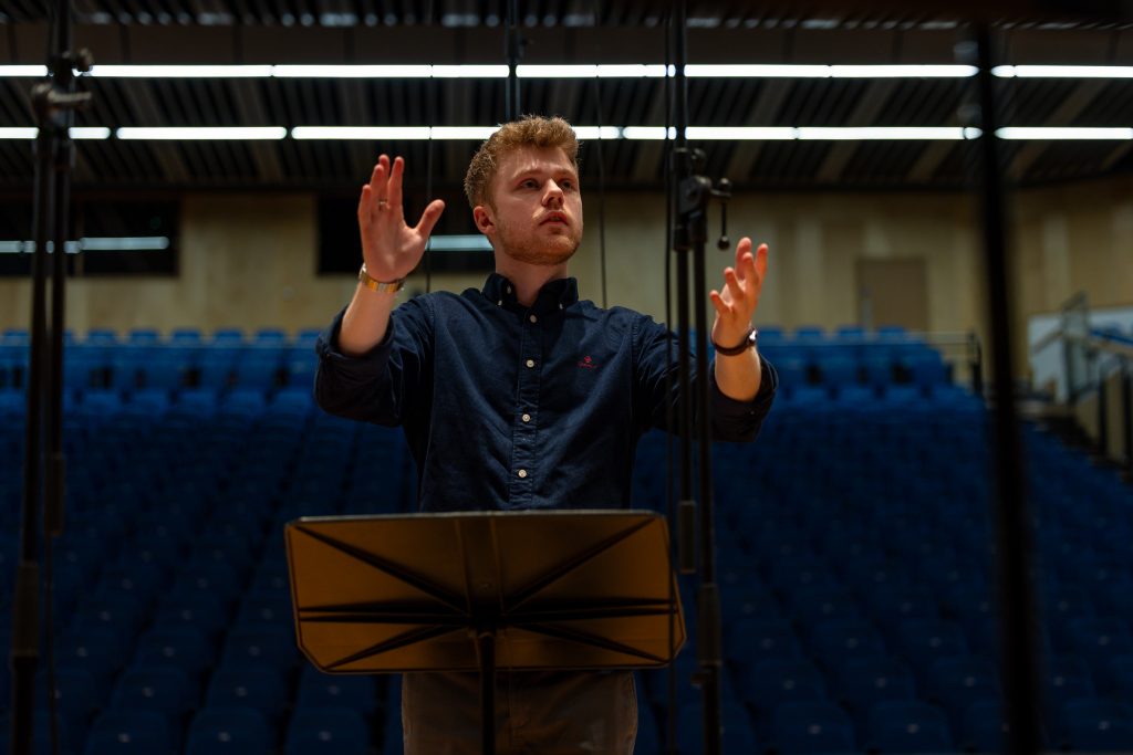 Adam Whitmore conducting with both hands raised in an expressive gesture