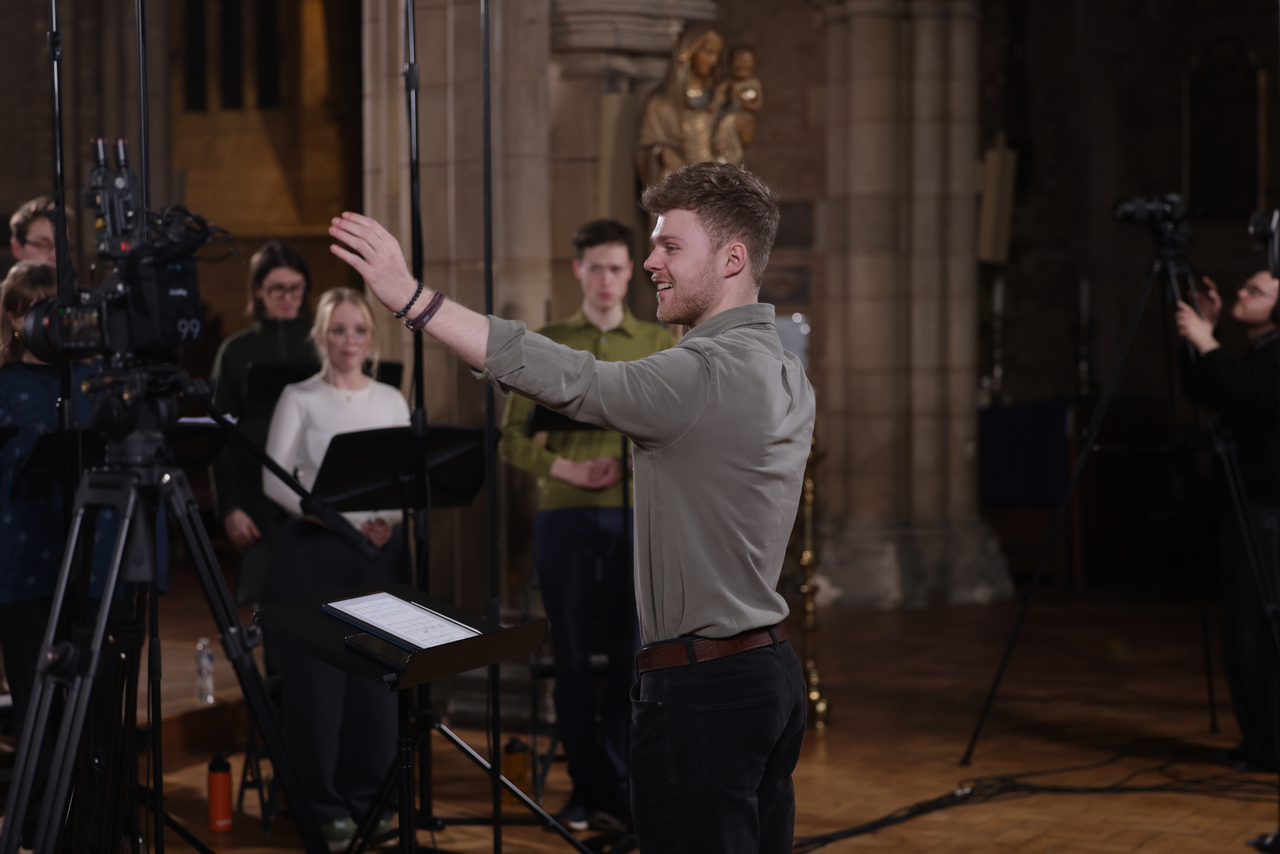 Adam Whitmore conducting a choir rehearsal in a cathedral setting