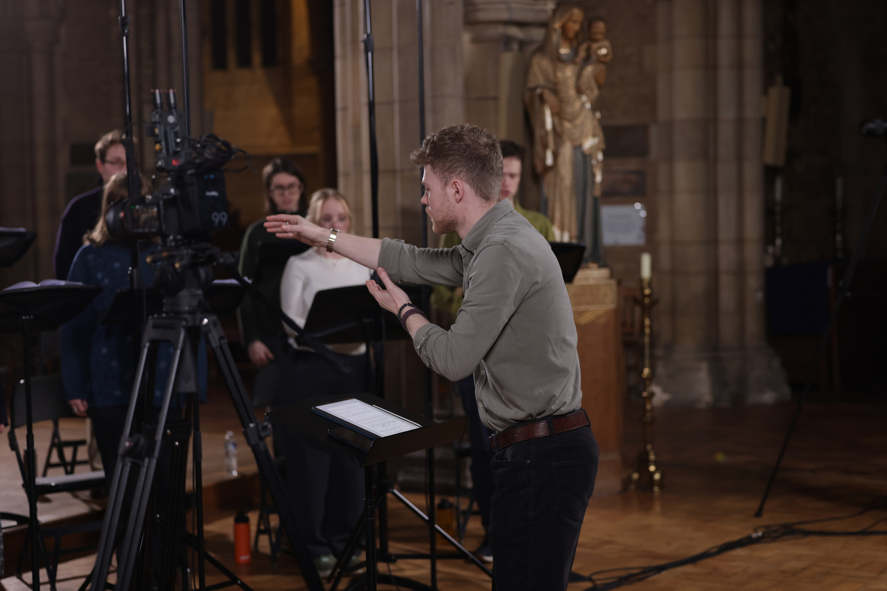 Adam Whitmore conducting The Phoenix Consort in cathedral with stone columns